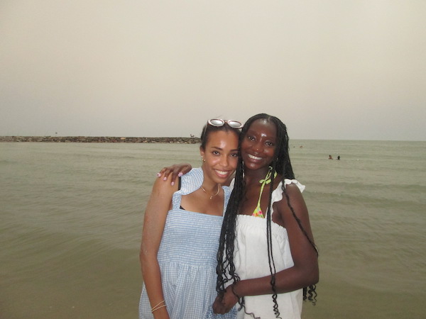 Two girls hugging in front of a body of water.