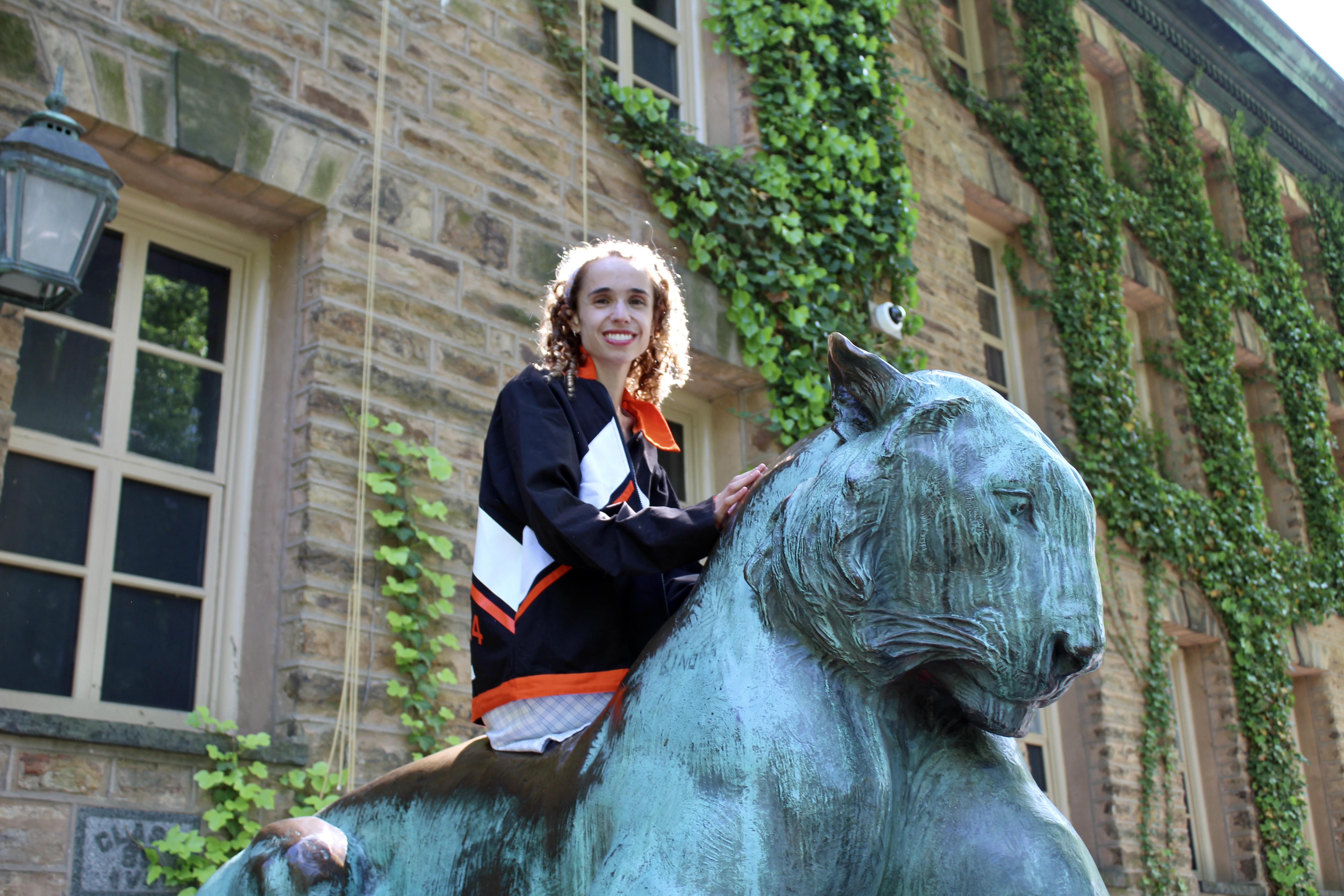 Author in class jacket sitting on bronze tiger